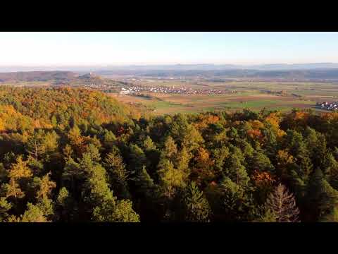 Flight over colourful forest and beautiful autumn landscape at sunset in Southern Germany