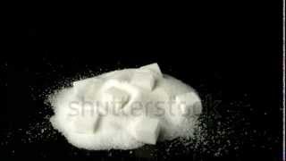 stock footage sugar cube falling in pile of sugar powder in slow motion