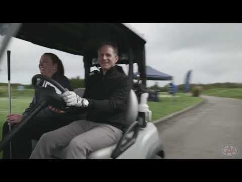 Two people driving in a golf cart.
