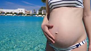 pregnant woman wearing swimsuit in swimming pool on vacation HD