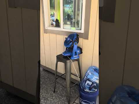 A misting fan spraying a fine cooling mist to keep outdoor workers cool on a hot summer day.