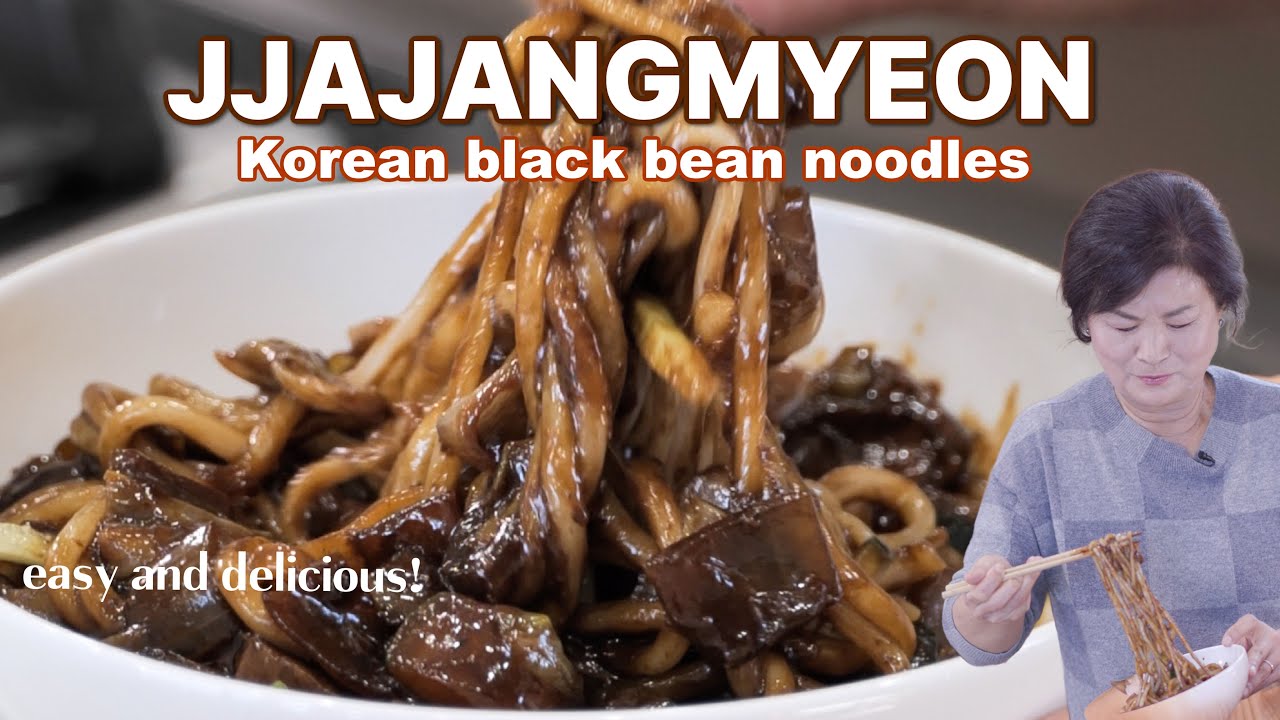 A bowl of Korean jajangmyeon noodles topped with thick dark black bean sauce diced pork and chopped scallions ready to be mixed and eaten
