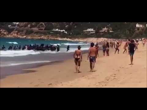 Migrant boat arrives at Spanish beach full of tourists,  Playa de los Alemanes in Tarifa