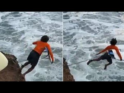 Terrifying moment surfer's lead is caught during cliff jump