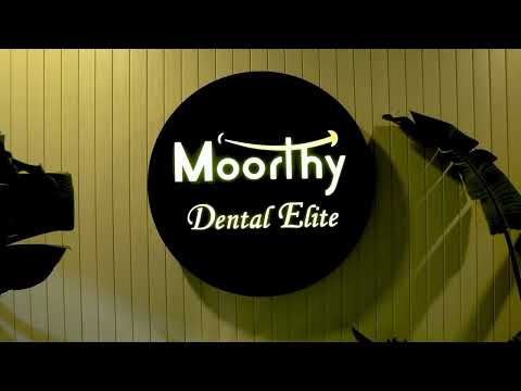 Backlit reception desk with warm wood slat wall at Moorthy Dental Elite