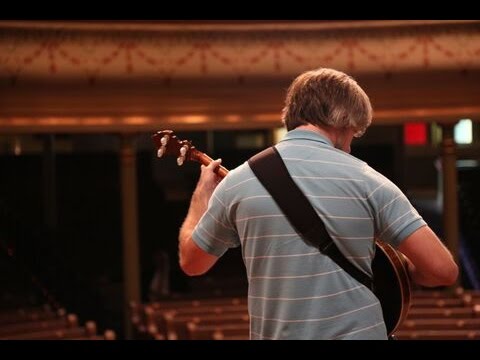 banjo player with his back turned in big auditorium