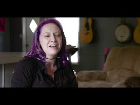 Trailer montage: sunburnt field, wristbands, and a pan over tents while a riff fades under VO