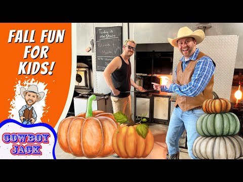 Two men in a blacksmith shop pose by a glowing forge; foreground pumpkins and a bright orange banner that says 'Fall Fun for Kids!' with a cartoon cowboy and 'Cowboy Jack' logo on the left.