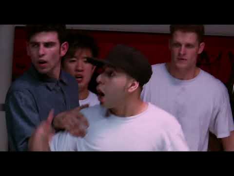 Mid-spin trailer frame: b-boy in air with crew reacting, rim lights flaring