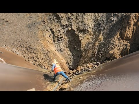 Barge unloading river sand and yellow phosphate rock - Large rock slides onto conveyor belt