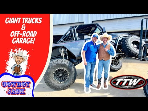 Two men in cowboy hats pose with a huge lifted off-road truck outside a garage, front and center, with bold red branding on the left and logos nearby.