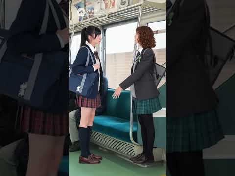 二人の女子高校生が電車の中で一つの空いた座席を取り合っている
