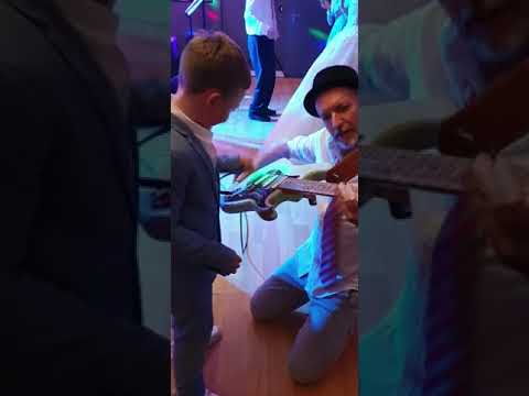 Sängerin der Hochzeitsband NRW spielt gemeinsam mit kleinem Jungen E-Gitarre neben dem Brautpaar auf der Tanzfläche bei einer Hochzeit