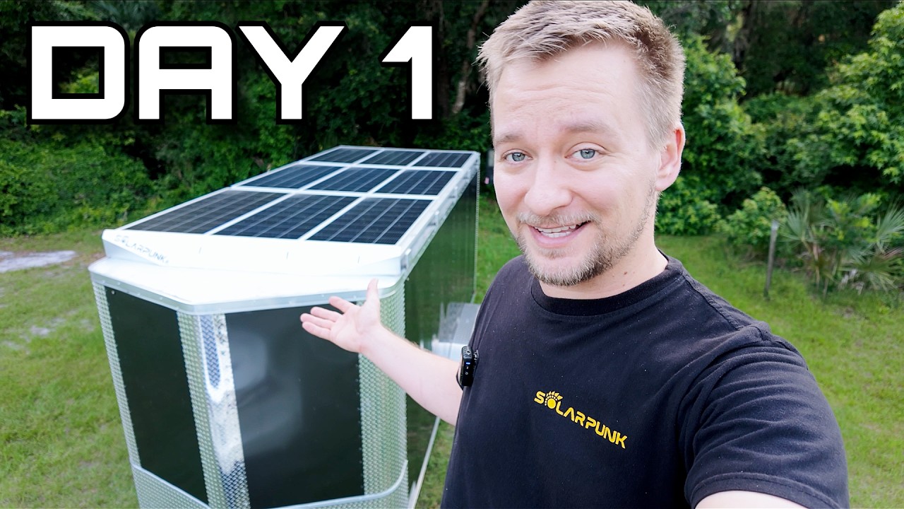 Solarpunk Steve standing in his Florida workshop next to his solar-powered trailer build on day one of winning the government contract