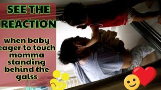 when baby eager to touch momma standing behind the glass