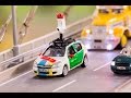 A miniature red, white and green Street View car crossing a model bridge