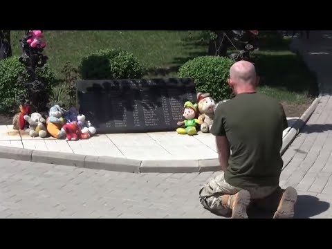 Ukrainian soldier knelt in front of the monument to the murdered children of Donbass