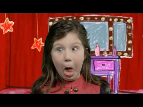 Girl on a playful stage backdrop making a goofy, surprised face with tongue out. Behind her is a red curtain and a cartoon dressing table with lights and stars.