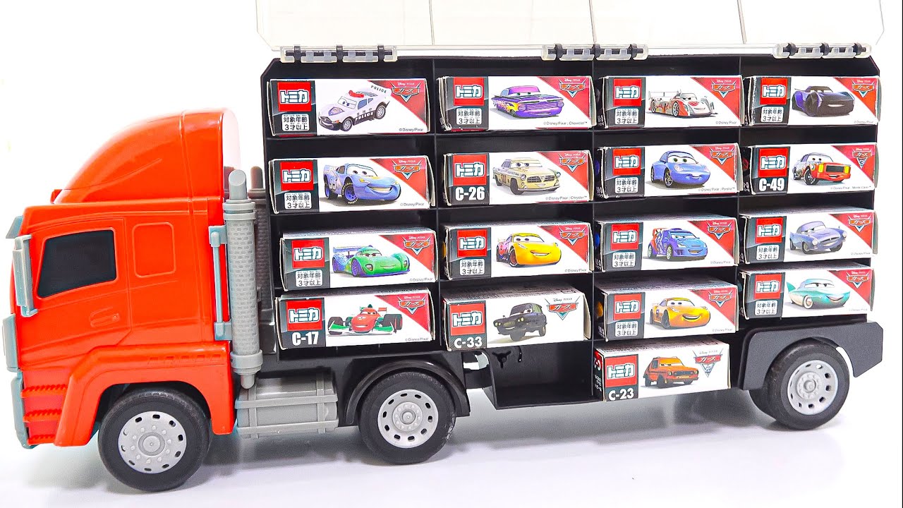 レッドトラックの中にカーズトミカが積載されている。そしてそれを開封する。
