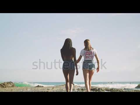 Two Best friend walking together along beach near the  ocean water.