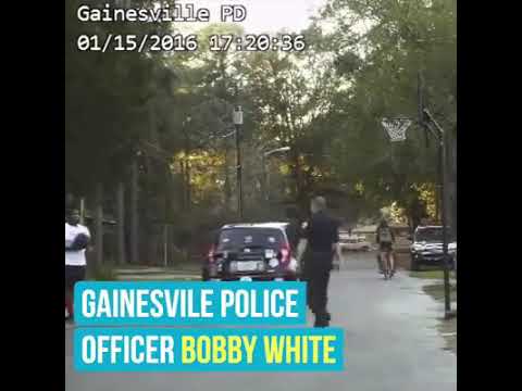 Basketball legend Shaq O'Neal and police officers play basketball with street youngsters.