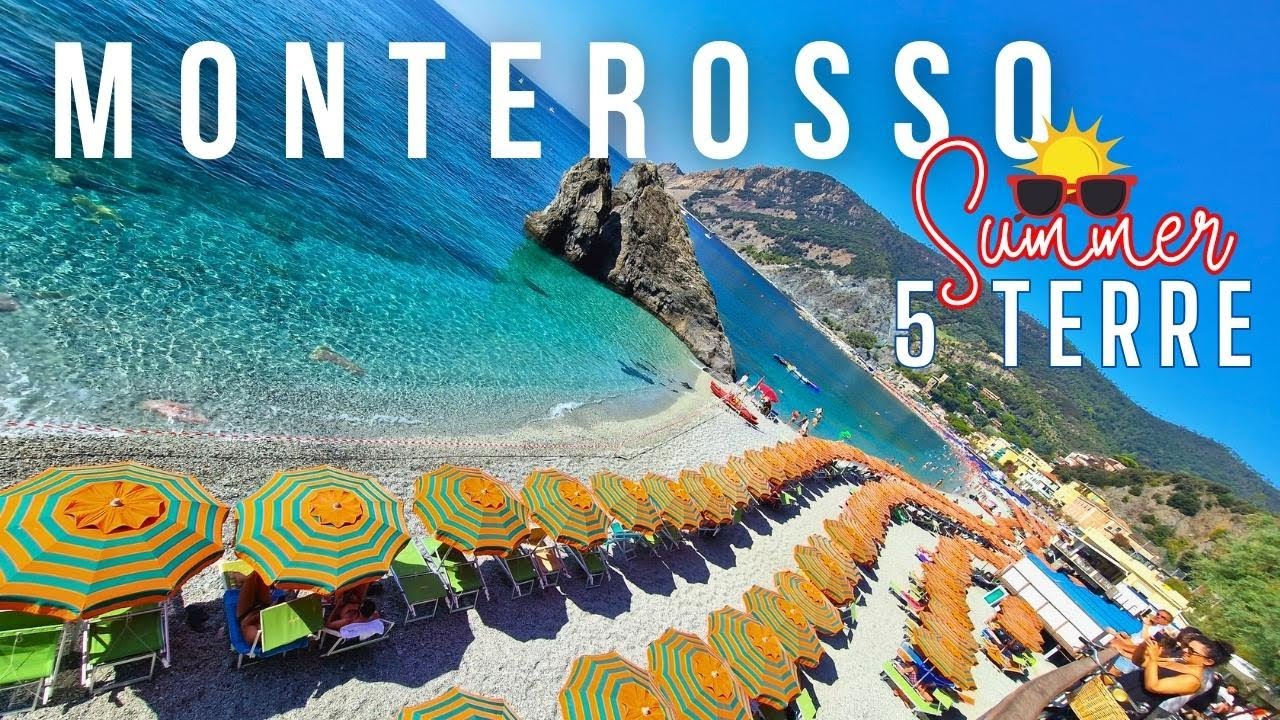 Experience Monterosso’s sandy beach through sweeping aerial views, showcasing its turquoise waters, vibrant umbrellas, and Cinque Terre's breathtaking coastal cliffs.