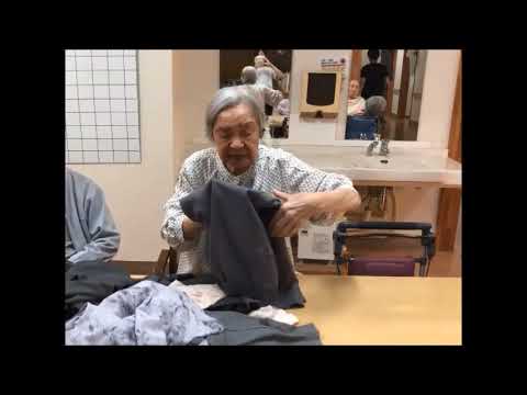入居者が洗濯物をたたむ日常生活風景。共用スペースでの活動様子。