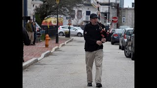 Kris Grills plays a medly of patriotic songs on the bagpipes for neighbors as he walks along Starr Street in New London