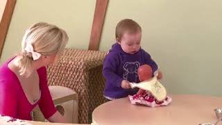 Connecting with practice: A very young child putting a bib on a doll