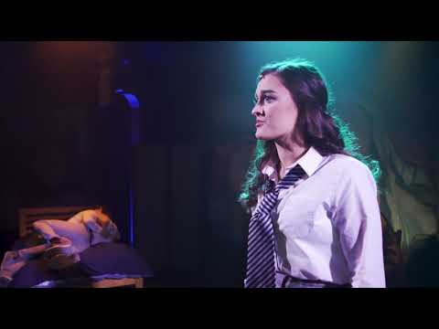 Cast gathered under a cruciform lighting pattern during a climactic tableau