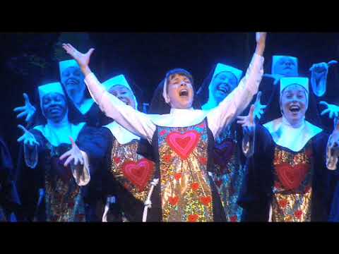 Trailer frame of the nun choir mid-modulation, hands clapping, brass blasting during the Raise Your Voice-to-finale arc
