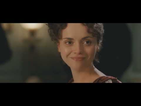 Trailer frame of salon gathering with chandeliers and guests, evoking the film's social arena