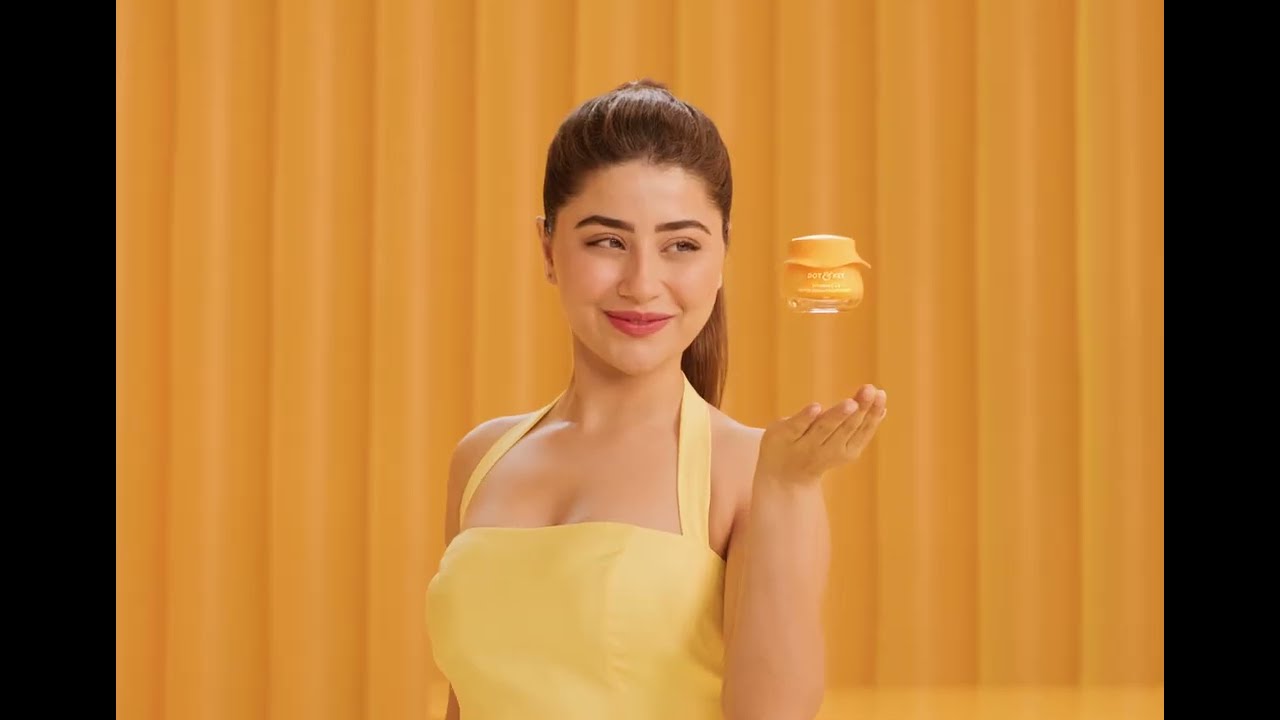 A woman glances at a floating moisturiser jar against a warm amber backdrop