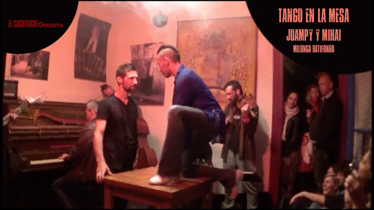 Juampy Ramirez y Mihai Goergescu bailan tango en la mesa de la milonga queer con El Cachivache