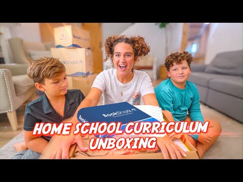 Three kids unbox a BookShark home-school curriculum box in a living room, with 'HOME SCHOOL CURRICULUM UNBOXING' text visible in the foreground.
