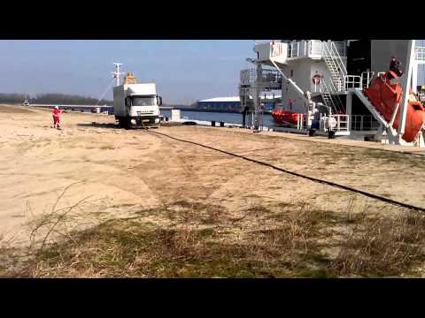 binnenschip pelikaan trekt vrachtwagen los uit mul zand