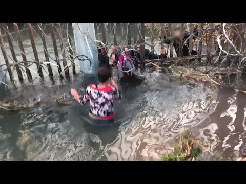 As sirens wail in the background, migrant smugglers push adults and children through a hole beneath a border wall in a video provided by US Customs and Border Protection. An advocate for the migrants says it shows their desperation. (April 2)