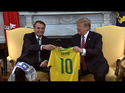 Brazil's new president, who has been dubbed the "Trump of the Tropics," has arrived at the White House for meetings with President Donald Trump. During an Oval Office photo-op, the two leaders exchanged national soccer jerseys. (March 19)