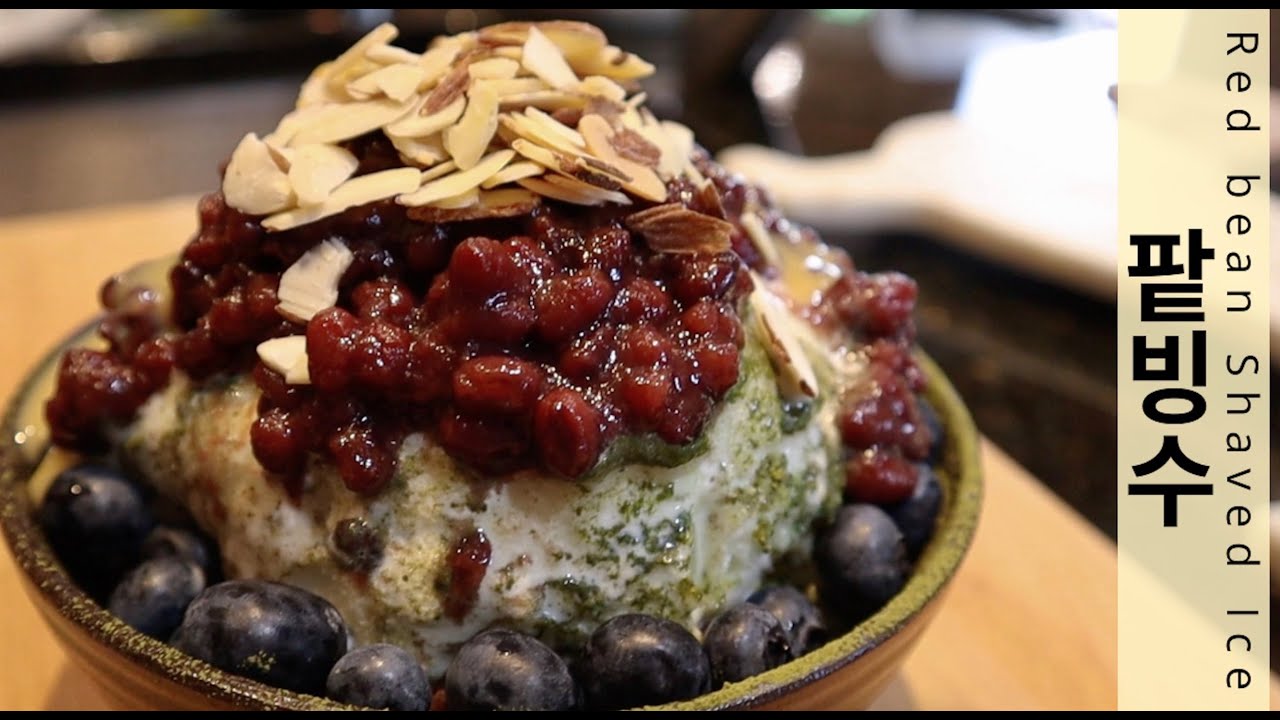 A bowl of Korean patbingsu shaved ice dessert topped with sweetened red beans condensed milk and mochi pieces for a colorful Korean summer treat