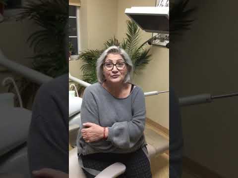 Woman in gray sweater sitting in dental treatment chair in West Caldwell