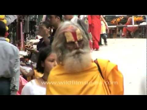 Woman flower seller and sadhu collects alms on streets of Kathmandu