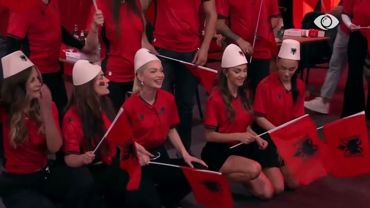 Te veshur kuqezi, banorët pozojnë para kamerave, teksa presin të nisë ndeshja