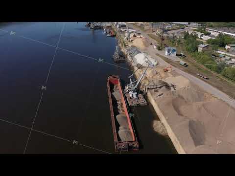 A harbor crane unloads a sand barge. Loading and unloading operations on the river. Aerial