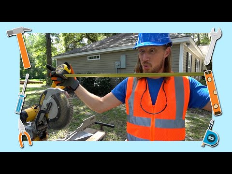 Construction worker in a blue hard hat and orange safety vest holds a level across a miter saw outdoors in front of a house.