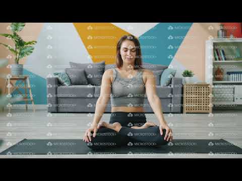 Attractive female adult working out in lotus position at home sitting on yoga mat