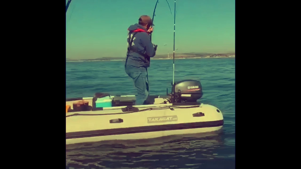 man in boat catching fish with rod