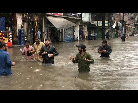 Pakistanis wade through waist-deep floodwater in Lahore after heavy rain | AFP