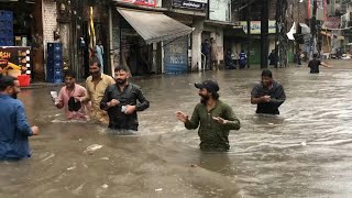Pakistanis wade through waist-deep floodwater in Lahore after heavy rain | AFP