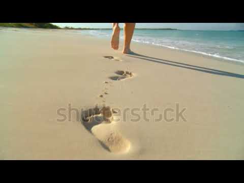 Young caucasian girl leaving footprints in the white sand of a tropical beach