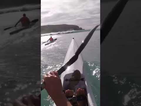 Surf ski paddling out through waves